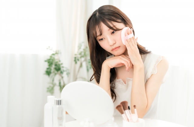 メイク中に落ち込む,悩む女性(肌荒れ)