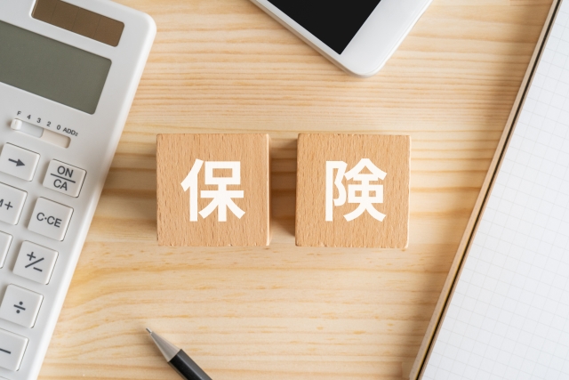 保険と書かれたブロック、電卓、スマホ
